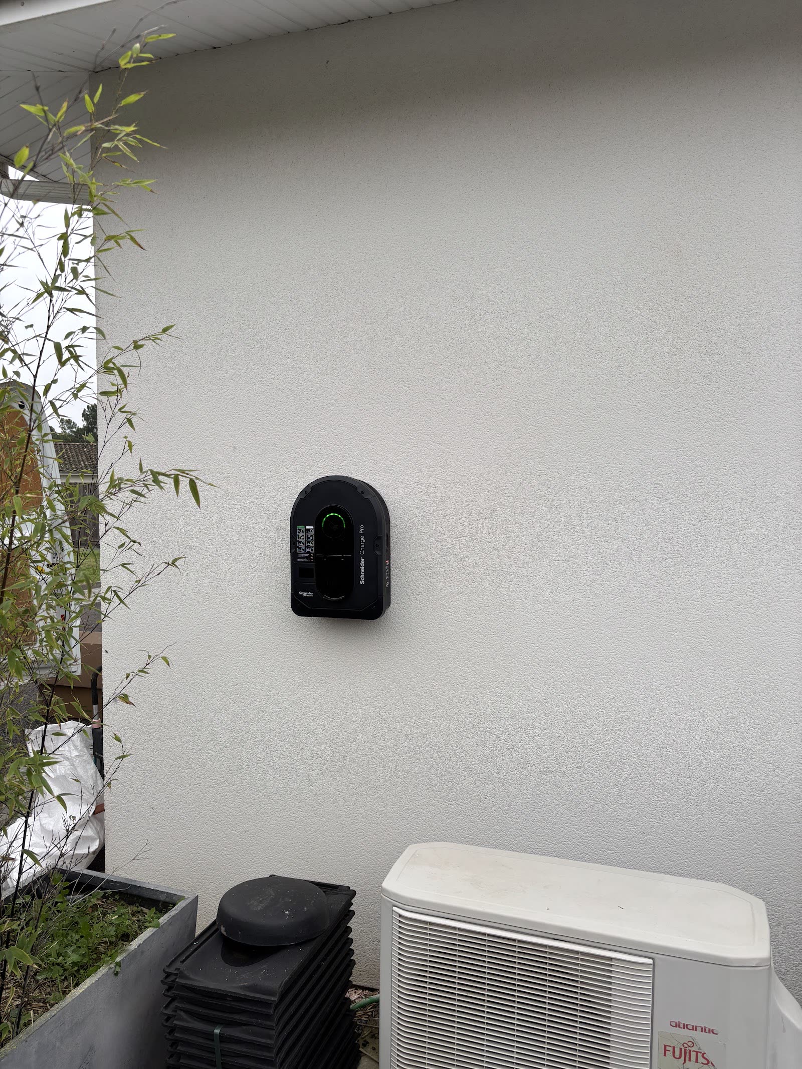 Borne de recharge installée sur un mur extérieur à proximité d’une unité technique